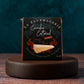 Box of La Fauxmagerie Camden Cultured smoked vegan cheese on a wooden stand with a dark background